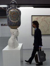 رجل يسير أمام تمثال لمهدي جورج لحلو 