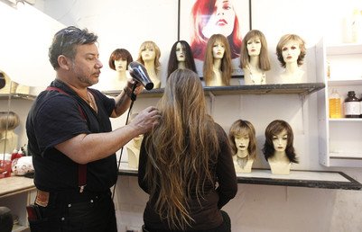 المصمم مارتشيللو آفاتي يقوم بتجفيف شعر المتبرعة باميلا ماتوس، قبل قصّه لعمل باروكة من الشعر الطبيعى 
