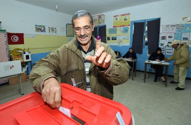 مواطن تونسي سعيد بالإدلاء بصوته في انتخابات جولة الإعادة يرفع إصبعه بالحبر الفوسفوري 21 ديسمبر