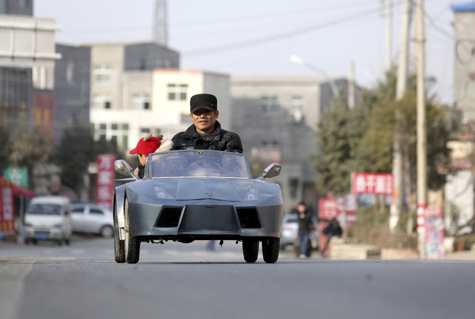 المزارع جيو الخمسيني مع حفيده يقودان سيارتهما المصنوعة يدويا كنسخة من سيارة لامبورجيني الإيطالية