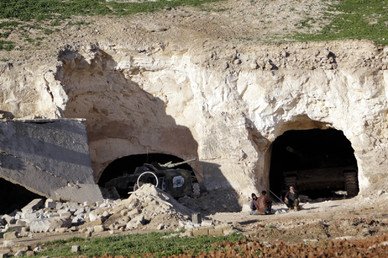 رجال يجلسون أمام كهف حفروه لإخفاء الدبابات، في منطقة حماة، 4 مارس 2015
