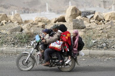 رجل يهرب على دراجته النارية برفقة أفراد عائلته وبعض الأمتعة