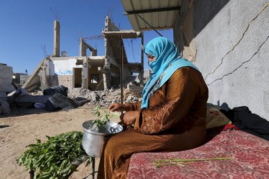 فلسطينية تحضر الطعام بجانب حطام منزلها، 22 يونيو 2015