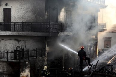 رجال الإطفاء يحاولون إخماد النيران المندلعة في المباني بقرية نيابولي في منطقة لاكونيا جنوب اليونان 
