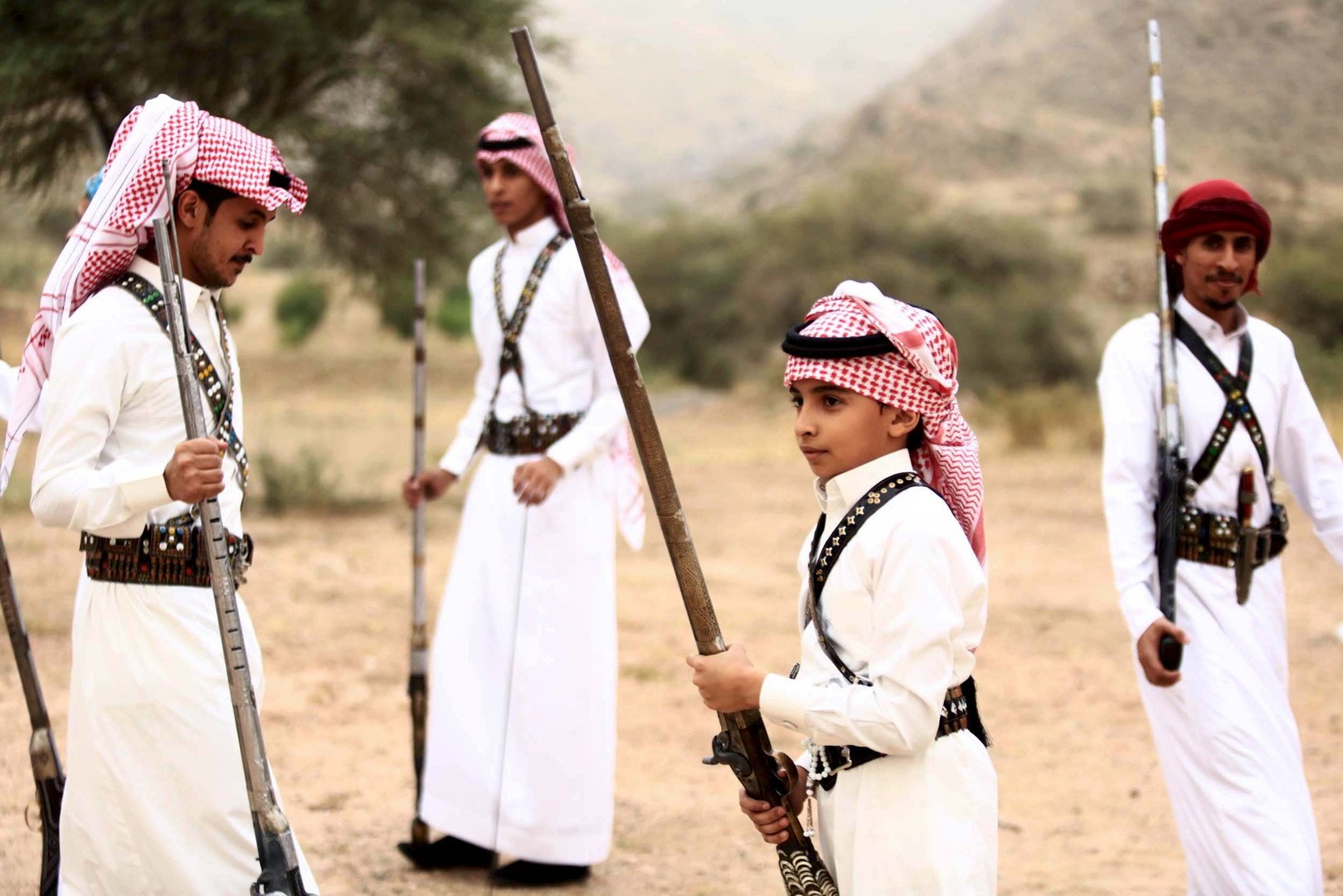 مجموعة من الأشخاص بينهم طفل يستعدون للتصوير وهم يحملون البنادق خلال أحد المناسبات بالقرب من مدينة الطائف في السعودية، 8 أغسطس 2015