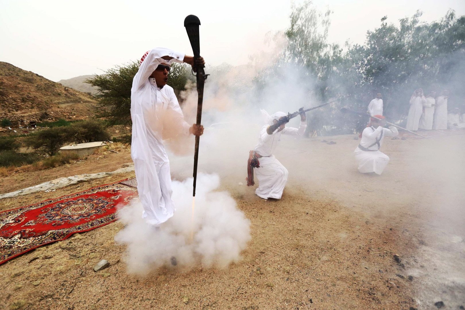  شخص آخر يطلق النيران على موضع قدميه خلال أحد المناسبات بالقرب من مدينة الطائف، بينما يرقص الآخرون بالبنادق، 8 أغسطس 2015