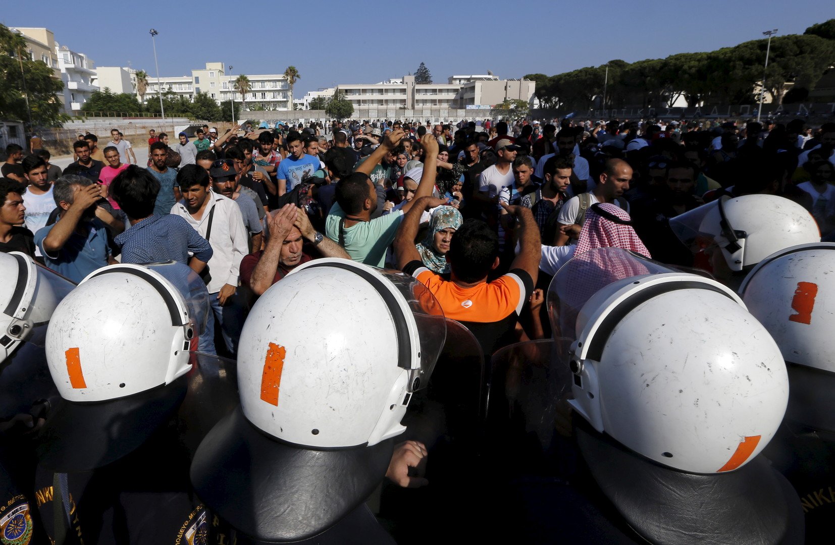 شرطة جزيرة كوس اليونانية تقف في مواجهة حشود اللاجئين السوريين في استاد الجزيرة الوطني، 11 أغسطس 2015 