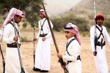 مجموعة من الأشخاص بينهم طفل يستعدون للتصوير وهم يحملون البنادق خلال أحد المناسبات بالقرب من مدينة الطائف في السعودية، 8 أغسطس 2015