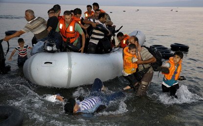  مجموعة من اللاجئين السوريين على متن قارب نجاة مزدحم يقتربون من شاطئ  جزيرة كوس اليونانية، 9 أغسطس/آب 2015