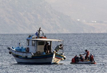 سفينة صيد يونانية تحاول مساعدة عائلة من اللاجئين السوريين على متن قارب نجاة، بعد تعطل محرك قاربهم، 11 أغسطس 2015