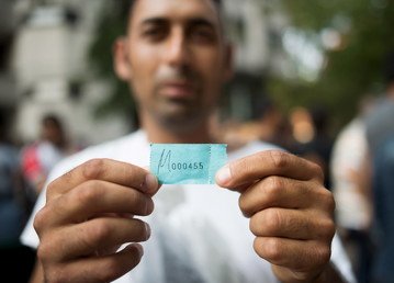 لاجئ حديث يظهر الرقم الذي حصل عليه من السلطات الألمانية من أجل الحصول على الإقامة 