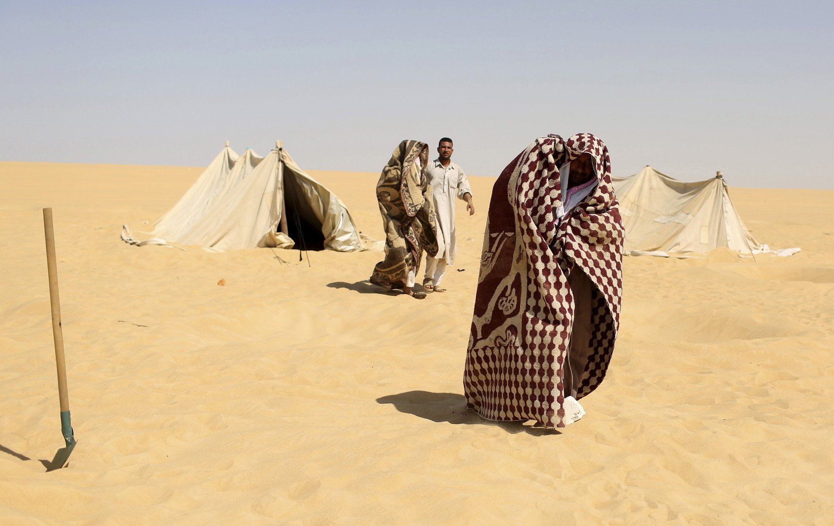 مستجمون يضعون أغطية بعد العلاج بحمام الرمال الساخنة في سيوة، مصر، 12 أغسطس 2015