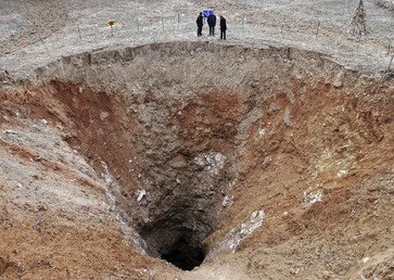 الناس يقفون بالقرب من الحفرة التي قطرها 24.9 مترا في مدينة غوانغيان بمقاطعة سيتشوان