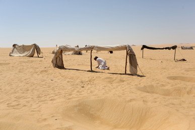 عامل يسوي الرمال  قرب خيمة قبل أن يستخدمها المستجمون وهي عبارة عن حمام بخاري "ساونا"، سيوة، مصر، 12 أغسطس/آب 2015