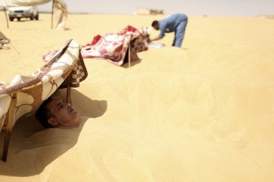 معالج يتفقد مستجمين تغطيهم الرمال في سيوة، مصر، 11 أغسطس 2015