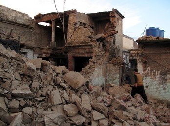  باكستاني يسير بين حطام الزلزال العنيف أمام منزله (26 أكتوبر/تشرين الأول 2015)