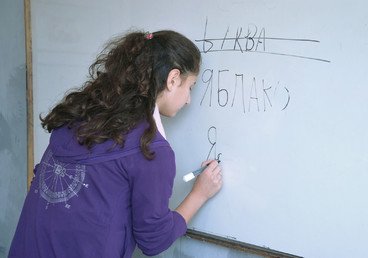 طالبة في الصف السابع  بمدرسة سهيل أبو الشملات تكتب كلمات روسية على اللوح
