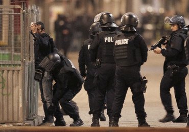 رجال الشرطة الفرنسية يوقفون أحد السكان المحليين لتفتيشه بعد حادث إطلاق النار في المنطقة