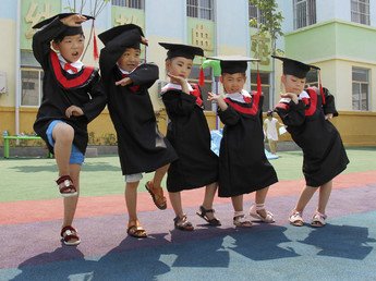 أطفال صينيون يرتدون عباءات وقلنسوات جامعية أثناء حفل التخرج من الروضة