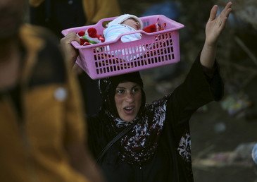 امرأة عراقية شردتها الحرب من مدينة الرمادي تحمل طفلها وتسير في ضواحي بغداد العاصمة