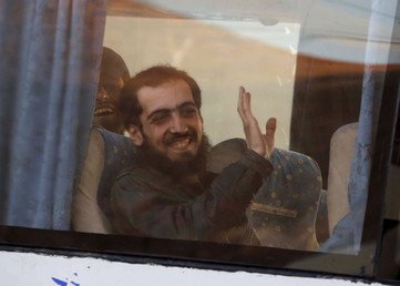 أحد المقاتلين من مدينة الزبداني المحاصرة يلوح بيده من داخل حافلة الإجلاء عند وصوله إلى المعبر الحدودي بين لبنان وسوريا، 28 ديسمبر/كانون الأول 2015. الإجلاء الذي تم في ظل اتفاق برعاية الأمم المتحدة.