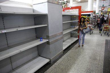 امرأة تمشي بجانب رفوف خالية من البضائع