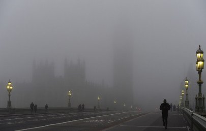 عمال يمشون على جسر وستمنستر في لندن في دكن الضباب