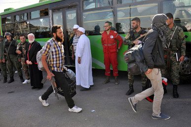جنود من الجيش السوري وعضو من الهلال الأحمر السوري لحظة خروج المقاتلين على متن حافلة لإخلاء وسط حمص، بموجب اتفاق بين المسلحين والجيش.
