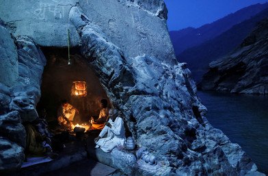 رهبان هندوس يجلسون داخل كهف على ضفة نهر الغانج بالقرب من مدينة ديفبراياغ الهندية أثناء أداء صلاتهم المسائية. 10 يوليو/ تموز 2017