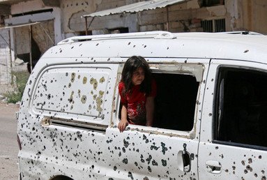 فتاة تنظر من حافلة عليها آثار أعيرة نارية في مدينة درعا السورية الجنوبية. 9 يوليو/ تموز 2017