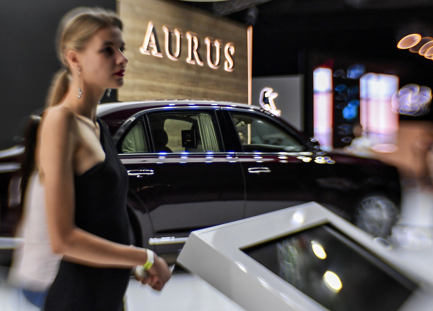 فتاة تقف أمام سيارة "Aurus Senat" في المعرض الدولي للسيارات لعام 2018