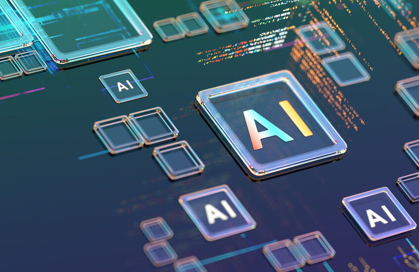 شريحة مربعة بارزة ومحاطة بإطار معدني لامع، ومكتوب عليها الحرفان "AI" بإضاءة متدرجة بين البرتقالي والأبيض، تنتشر حولها عدة رقاقات أصغر حجما تحمل أيضا شعار "AI"