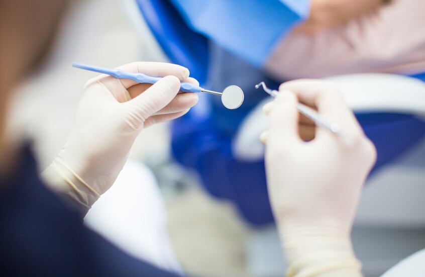 لقطة لطبيب أسنان ذكر أثناء العمل، وهو يرتدي قفازات جراحية ويمسك أدوات طب الأسنان.