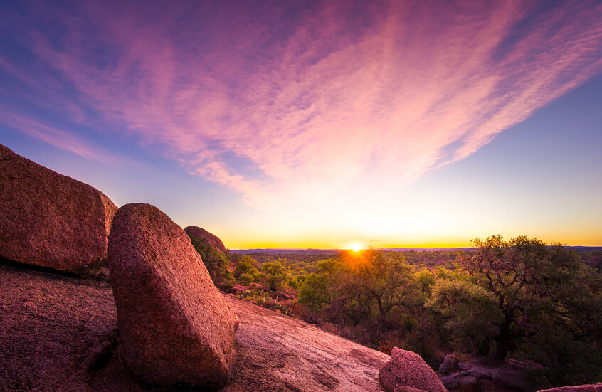 لحظة شروق الشمس فوق منتزه "إنشانتد روك" الحكومي (Enchanted Rock State Natural Area)، وتظهر صخرة الغرانيت الوردية الضخمة