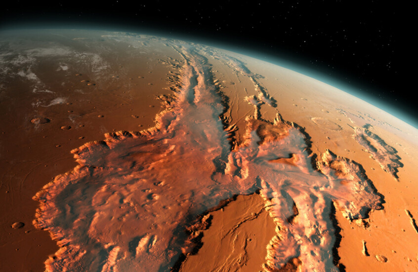 رسم توضيحي يقدم مشهدا مائلا لنظام أخاديد وادي مارينير (Valles Marineris) العملاق على كوكب المريخ، يبرز الوادي كشق ضخم يقطع سطح الكوكب الأحمر، ممتدا عبر مسافات شاسعة، وتهيمن درجات اللون البرتقالي، البني المحمر، والترابي على السطح