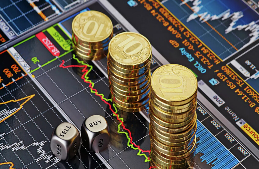 أكوام من عملات معدنية من فئة 10 روبلات أمام شاشة تعرض رسوما بيانية لحركة التداول